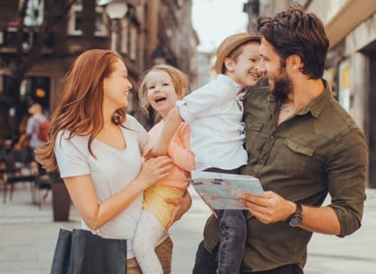 Photo of parents, their son, and their daughter outdoors with a downtown city-like scene in the background, for family dentistry from Dr. William Becker of Hoffman Estates.
