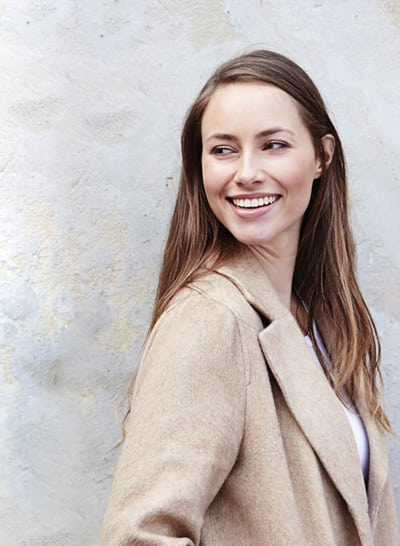 Head-and-shoulders photo of brunette woman with long hair smiling and looking over her right shoulder, for information on porcelain veneers from Hoffman Estates cosmetic dentist Dr. William Becker.