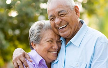Head-and-shoulders photo of elderly couple hugging and smiling for information on affordable dentistry, from Poplar Crossing Dental in Hoffman Estates.