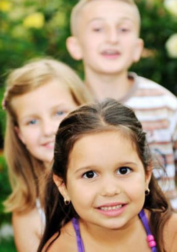 Photo of three children - one standing behind another. In front is a brunette girl with brown eyes, about four years old. Behind her is a blonde girl with long hair and blue eyes, about 7 years old, and behind her is a blonde boy with dark eyes, about 12 year old, for information on dental tips for parents from Hoffman Estates Dr. Becker.