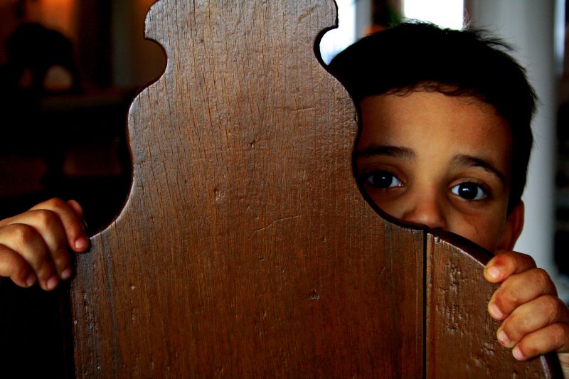 boy cowering behind chair