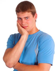 Young man in pain holding the side of his cheek from a toothache